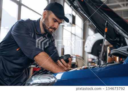 Focused at work. Mechanic is in a car service station Focused at work. Mechanic is in a car service station 134673792