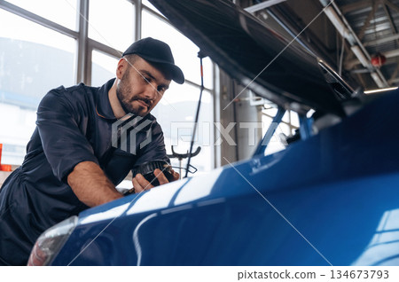 Focused at work. Mechanic is in a car service station 134673793
