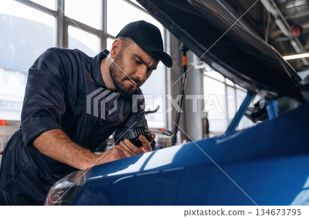 Focused at work. Mechanic is in a car service station 134673795
