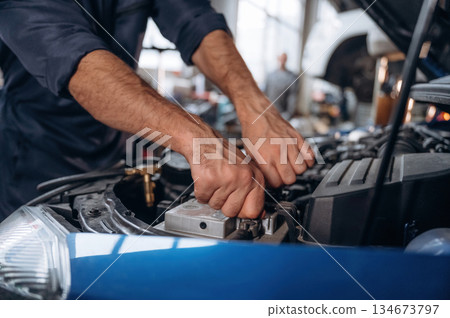 Blue automobile, working. Close up view of mechanic in car service station 134673797