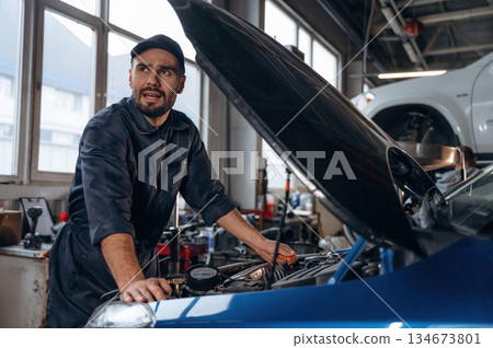 In the cap, busy. Mechanic working in a car service station In the cap, busy. Mechanic working in a car service station 134673801