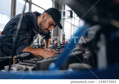 Transport is being repaired. Mechanic working in a car service station Transport is being repaired. Mechanic working in a car service station 134673803