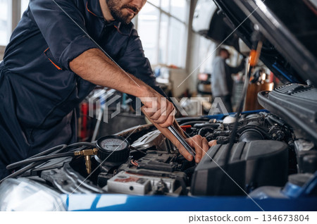Opened hood. Close up view of mechanic in car service station Opened hood. Close up view of mechanic in car service station 134673804