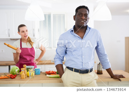 Portrait of positive man and his wife in kitchen at home Portrait of positive man and his wife in kitchen at home 134673914