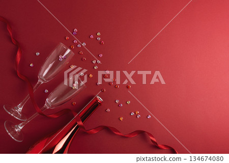 Champagne Bottle and Glasses with Colorful Hearts on Red Background. Valentines Day Celebration 134674080