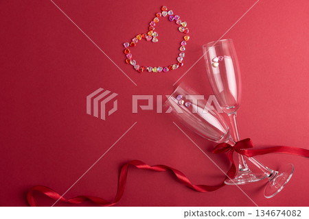 Champagne Flute Glasses with Colorful Heart made from Confetti on Red Background. Valentines Day Celebration Champagne Flute Glasses with Colorful Heart made from Confetti on Red Background. Valentines Day Celebration 134674082