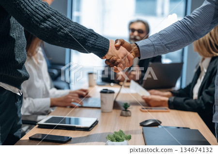 Deal, doing handshake. Group of office workers are indoors together Deal, doing handshake. Group of office workers are indoors together 134674132