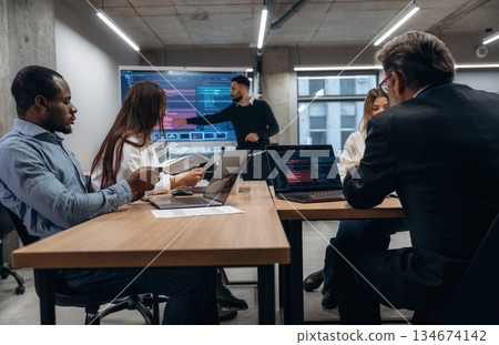 Data on screen. Group of office workers are indoors together Data on screen. Group of office workers are indoors together 134674142