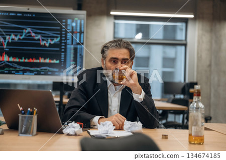 Drinking alcohol, depression. Senior man is in the modern office Drinking alcohol, depression. Senior man is in the modern office 134674185