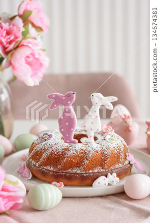 Traditional easter cakes with icing decorated with gingerbread cookies in shape of rabbits on white wooden table 134674381