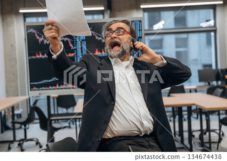 Screaming, talking by phone. Senior man is in the modern office Screaming, talking by phone. Senior man is in the modern office 134674438