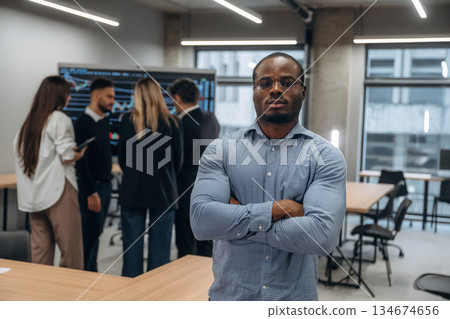 African American man is standing against his colleagues. Group of office workers are indoors together 134674656