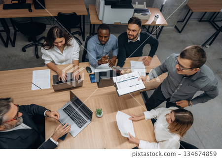 View from the top, by the table. Group of office workers are indoors together 134674859
