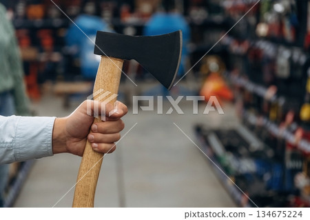 An axe in hand. Detailed close up view of man's hand in the hardware store 134675224