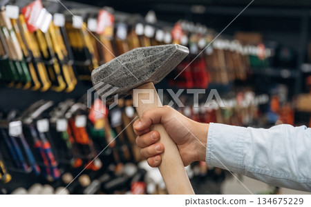 The hammer in hand. Detailed close up view of man's hand in the hardware store The hammer in hand. Detailed close up view of man's hand in the hardware store 134675229