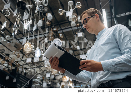 Reading documents. Male hardware store worker in indoors Reading documents. Male hardware store worker in indoors 134675354