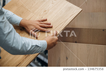 Surface of the parquet. Detailed close up view of man's hand in the hardware store 134675358
