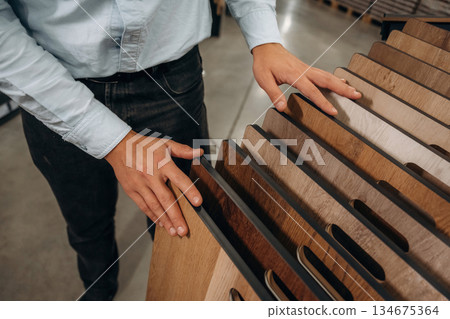 Wooden parquet. Detailed close up view of man's hand in the hardware store Wooden parquet. Detailed close up view of man's hand in the hardware store 134675364