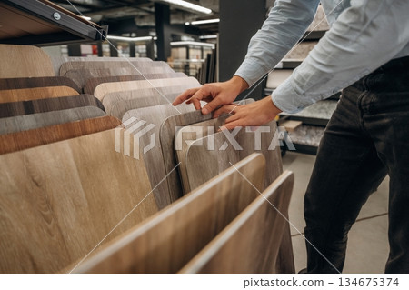 Big choice of parquet. Detailed close up view of man's hand in the hardware store Big choice of parquet. Detailed close up view of man's hand in the hardware store 134675374