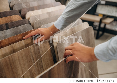 Big choice of parquet. Detailed close up view of man's hand in the hardware store Big choice of parquet. Detailed close up view of man's hand in the hardware store 134675375