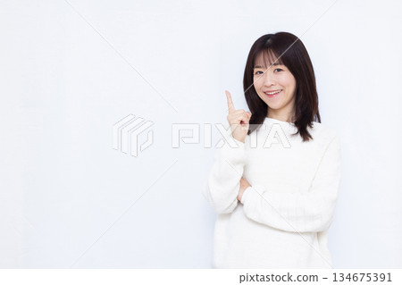 Smiling woman pointing up her index finger Smiling woman pointing up her index finger 134675391