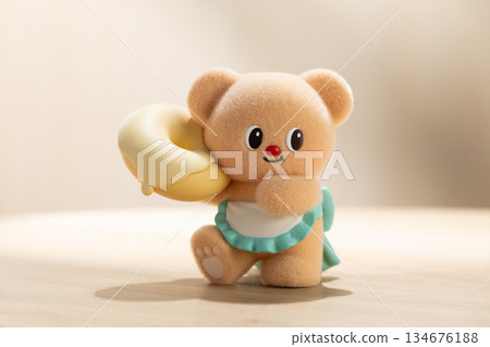 Backlit ButterBear Toy Holding a Large Donut on Fabric Surface 134676188