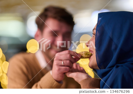 Together at iftar in Ramadan, a couple sharing food and joy among festive decorations in a lively setting 134676296