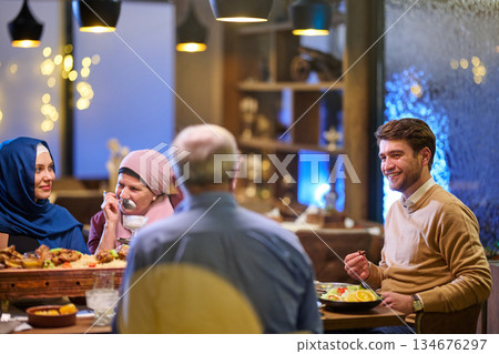 Families share iftar meals together during Ramadan in a cozy restaurant setting with warm lights and festive decor Families share iftar meals together during Ramadan in a cozy restaurant setting with warm lights and festive decor 134676297