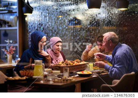 Gathering around the table to break fast during Ramadan with family and friends in a cozy restaurant Gathering around the table to break fast during Ramadan with family and friends in a cozy restaurant 134676303