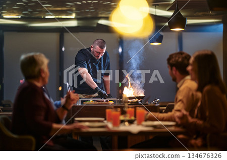 Gathering with family for iftar at a restaurant during Ramadan with a chef preparing food 134676326