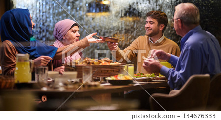 Family gathers for iftar during Ramadan with shared meals and conversations at a cozy dining table 134676333
