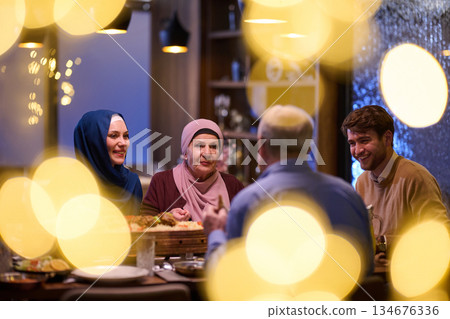 Family gathers around table for iftar during Ramadan with food, laughter, and conversation in home setting 134676336