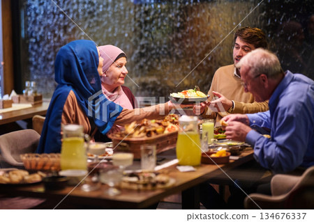 Family gathering for iftar during Ramadan with a spread of traditional dishes and drinks in a cozy restaurant setting 134676337