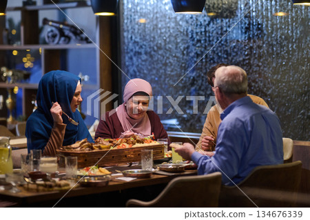 Gathering for iftar with family members sharing food and laughter during Ramadan in a warm dining environment 134676339