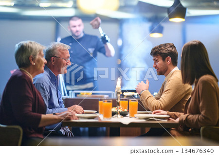 Family gathers for iftar to break fast during Ramadan in a restaurant setting with a chef preparing meals in the background Family gathers for iftar to break fast during Ramadan in a restaurant setting with a chef preparing meals in the background 134676340