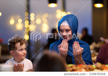 Family members gather for iftar during Ramadan, sharing food and prayers with joy and connection in a cozy setting 134676348
