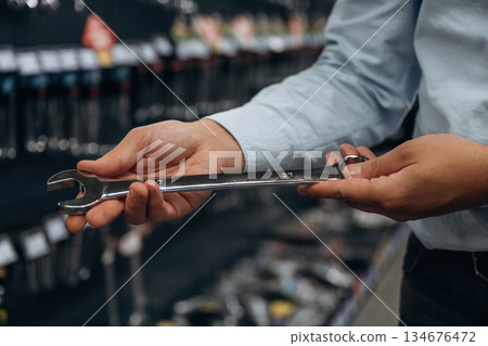 Wrench in hand. Detailed close up view of man's hand in the hardware store Wrench in hand. Detailed close up view of man's hand in the hardware store 134676472