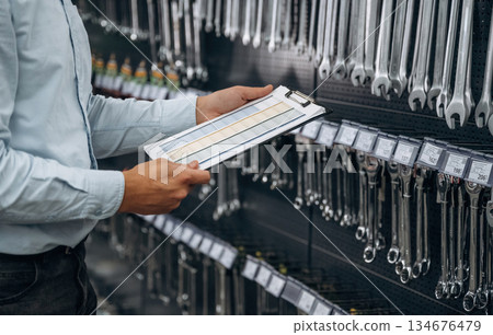 Document in notepad. Detailed close up view of man's hand in the hardware store Document in notepad. Detailed close up view of man's hand in the hardware store 134676479