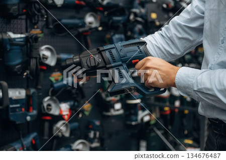 Perforator drill. Detailed close up view of man's hand in the hardware store Perforator drill. Detailed close up view of man's hand in the hardware store 134676487
