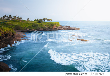 Tanah Lot coastline dramatic ocean cliffs and tropical shore near Bali temple area create calm travel mood with blue water, volcanic rocks, Bali coastal nature and open horizon under soft daylight Tanah Lot coastline dramatic ocean cliffs and tropical shore near Bali temple area create calm travel mood with blue water, volcanic rocks, Bali coastal nature and open horizon under soft daylight 134676999