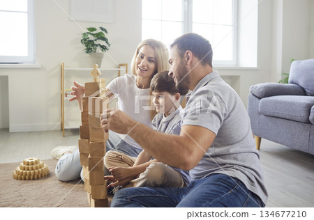 Young happy family playing kid boy building wooden pyramid in the living room at home 134677210