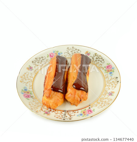 Two chocolate eclairs served on a vintage floral porcelain plate. 134677440