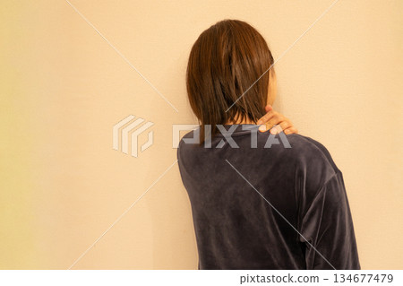 一位女士肩膀僵硬，她正用手扶著自己的肩膀。 134677479