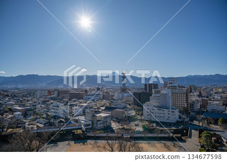 A view of the cityscape with the shining sun and Mt. Fuji from the castle tower of Maizuru Castle Park [Kofu City, Yamanashi Prefecture] 134677598