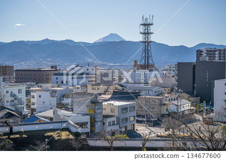 Mount Fuji towering above the white walls of Kofu Castle and the modern cityscape [Kofu City, Yamanashi Prefecture] 134677600