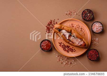 A hot dog with sausage, bacon, sauces, and a bun, unhealthy takeaway food. A hot dog with bacon A hot dog with sausage, bacon, sauces, and a bun, unhealthy takeaway food. A hot dog with bacon 134678693
