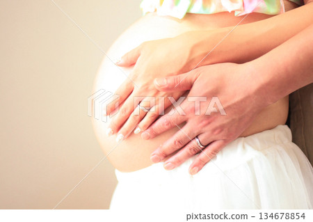 Belly and hands of a pregnant woman about to give birth. 134678854