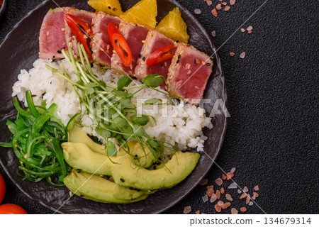 Seared tuna tataki in a bowl with sesame seeds, rice, and vegetables. Tuna tataki 134679314
