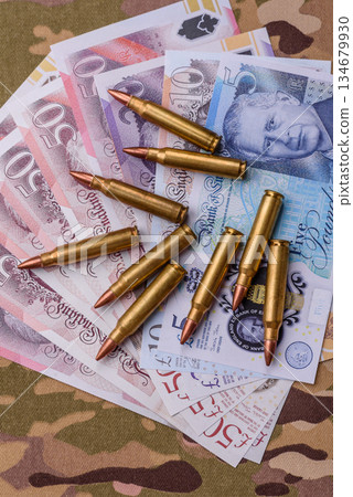 Machine gun cartridges on a camouflage background, military wallpaper. Camouflage background Machine gun cartridges on a camouflage background, military wallpaper. Camouflage background 134679930