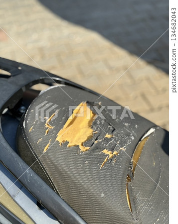 Ripped motorcycle seat with visible damage and exposed foam, suitable for background use Ripped motorcycle seat with visible damage and exposed foam, suitable for background use 134682043